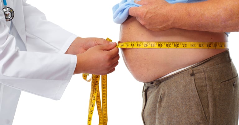A doctor measuring an overweight man's waist circumference with a yellow tape measure.