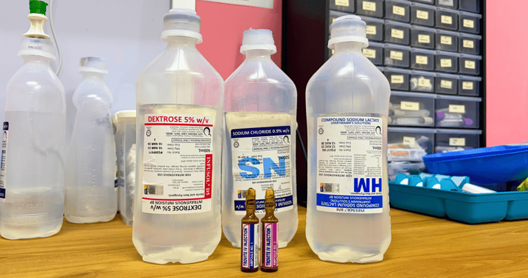 Dextrose, sodium chloride, and compound sodium lactate intravenous infusion bottles on a clinic desk.