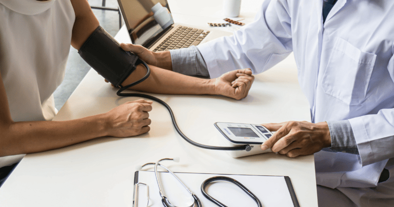 A healthcare professional checking a patient's blood pressure using a digital monitor during a medical consultation.