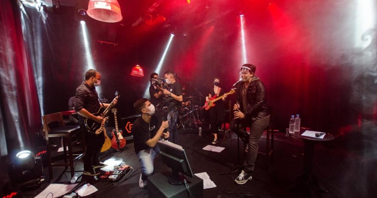 banda tocando num palco com fundo preto e luzes vermelhas e brancas