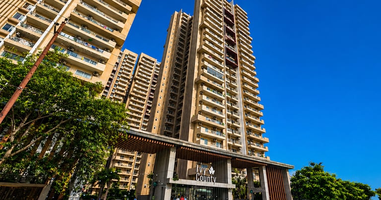 Luxurious high-rise Ivy County residential apartments in Noida under a clear blue sky.