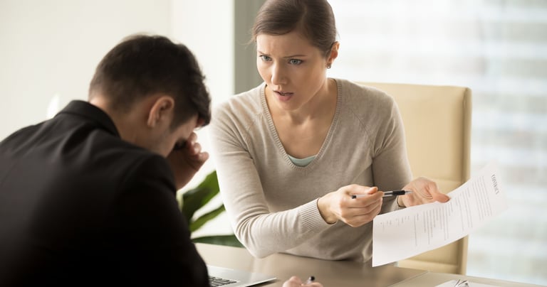 a man and woman sitting at a table with papers