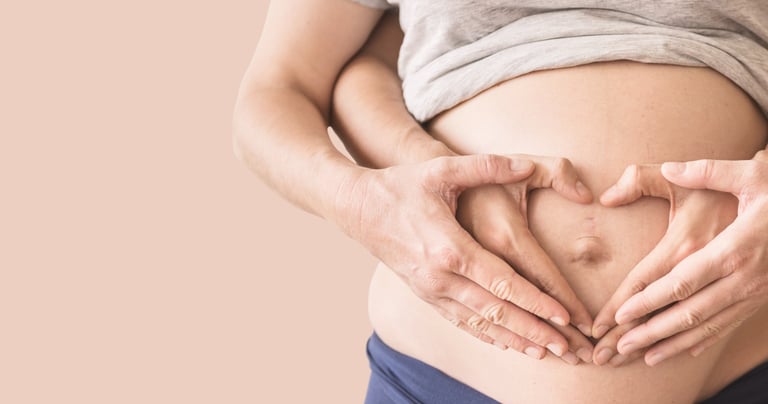 a pregnant woman holding her hands in the shape of a heart