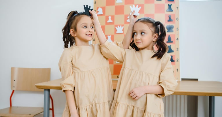 two young girls standing in front of a chess board
