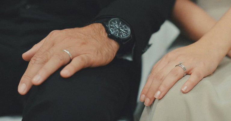 a man and woman holding hands and wearing rings