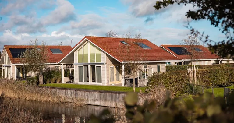  Luxuriöse Ferienhaus in einem Ferienpark direkt am Wasser mit Solaranlage und rotem Ziegeldach.