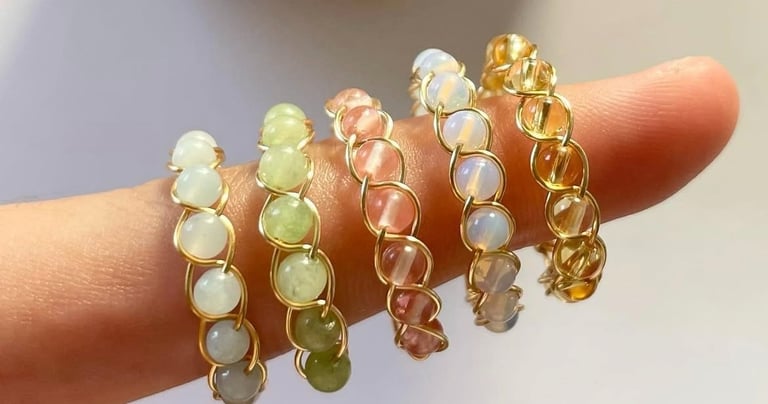 Anillos de alambre dorados con cuentas de diferentes colores en un dedo.