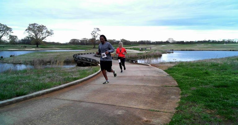 A photo of runners racing acoss a bridge at the Rober Trent Jones Running the Shoals Marathon
