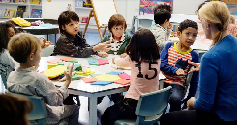 A teacher giving a group of students feedback as they work collaboratively on a task.