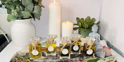 A serene arrangement featuring various essential oil bottles on a wooden tray surrounded by dried he