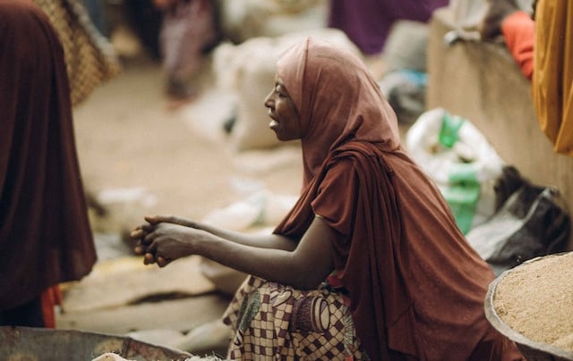 a woman in a red dress sitting on a pile of bags