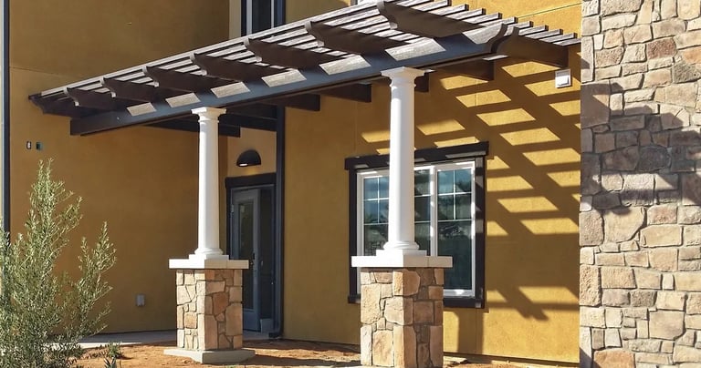Spanish Brown Alumawood shade structure with decorative round columns on stone faced base.