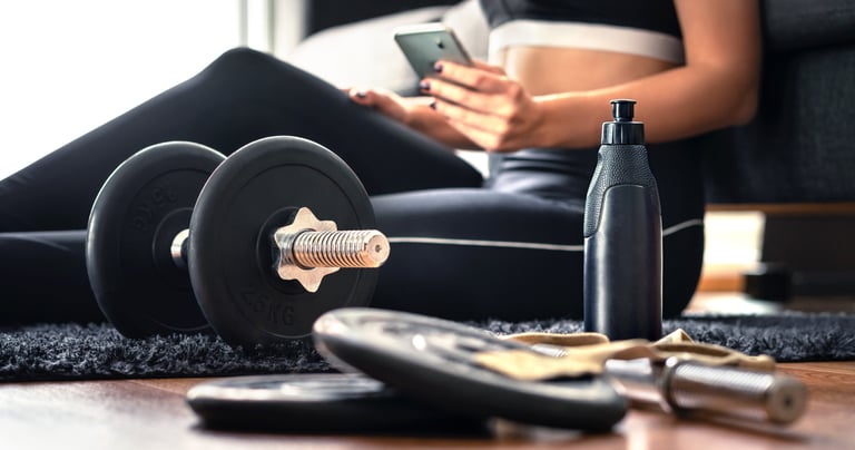 Online personal training at home—woman on lounge room floor with dumbbells and plan, virtual coachin