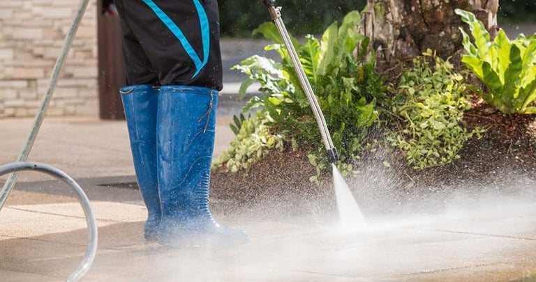Man pressure washing sidewalk