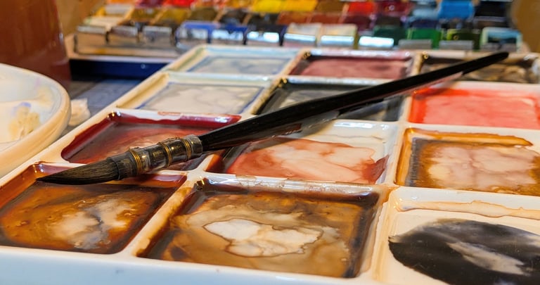 Waterverf palet met penseel en aquarel napjes, gemengde kleuren op een bord