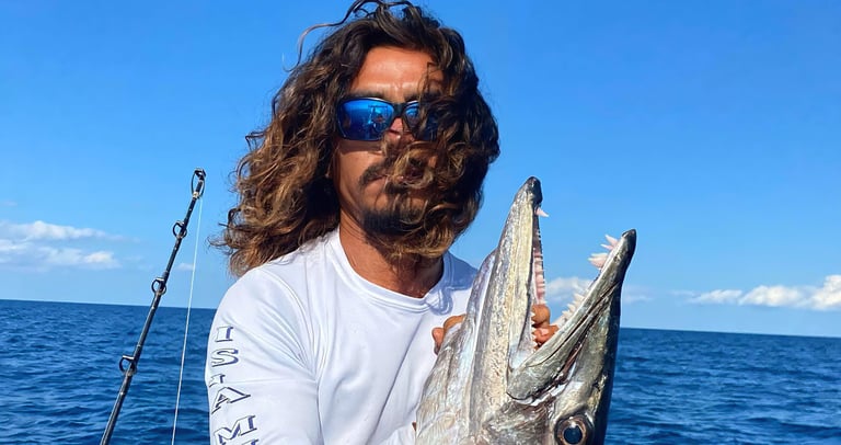 a man with a beard and sunglasses holding a fish