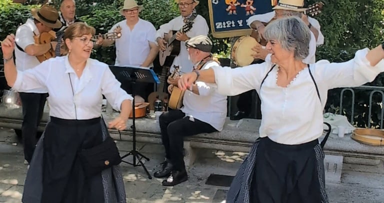 Dos mujeres bailan una jota mientras una banda de música escofolk toca música.
