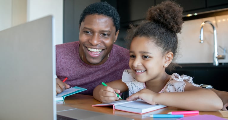 Dad home educating daughter in NZ via laptop and using a notebook.