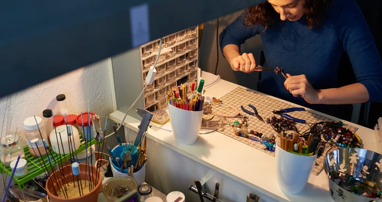 Mujer trabajando en un taller,con piedras y herramientas de macramé