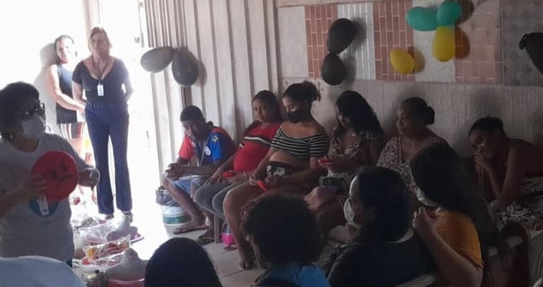A community health workshop for pregnant women and families seated in a decorated room.