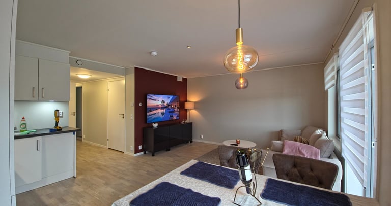 Modern open plan living room and kitchen featuring a dining table, pendant light, and wall-mounted TV.