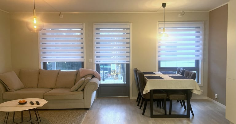 Modern open plan living room and dining area with neutral sofa, wooden floors, and white stripes.