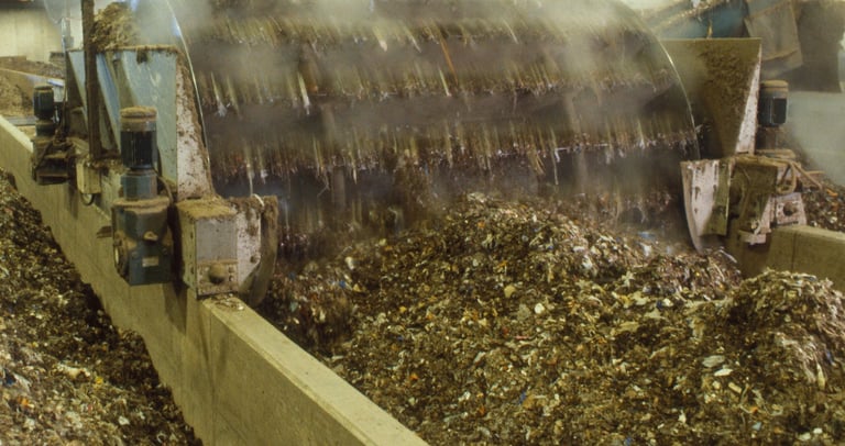Industrial composting machine processing organic waste with steam in a large-scale recycling facility.