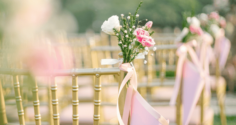 a row of chairs with pink ribbon tied to them