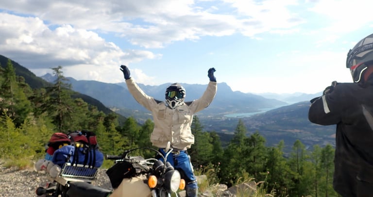 a man standing on a mountain top with his arms up in the air
