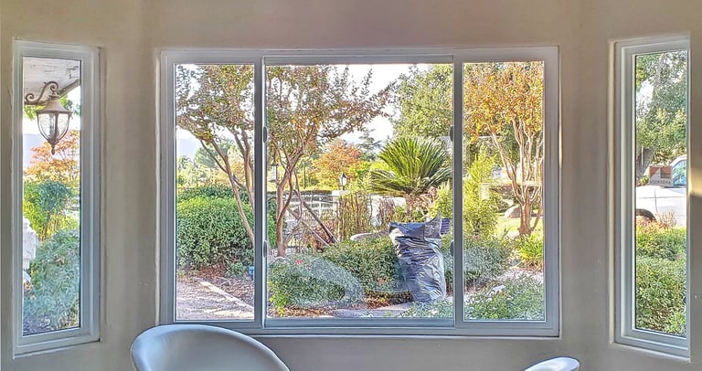 View of garden through white bay windows.