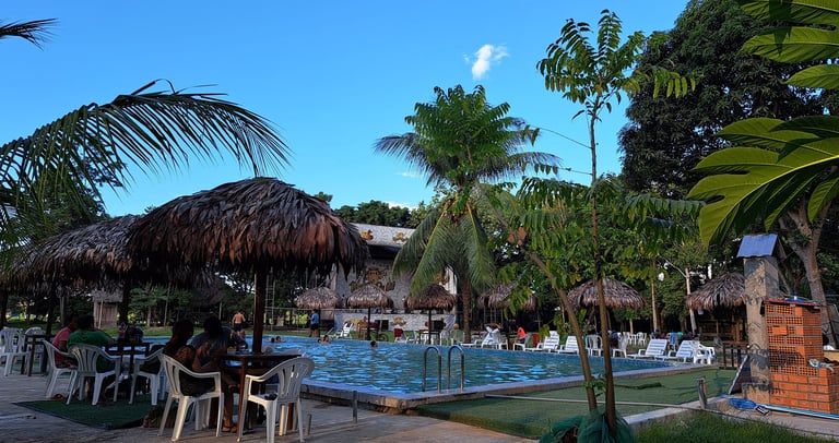 Centro Recreacional Mokanranko with thatched umbrellas, palm trees, and guests relaxing at the pool.