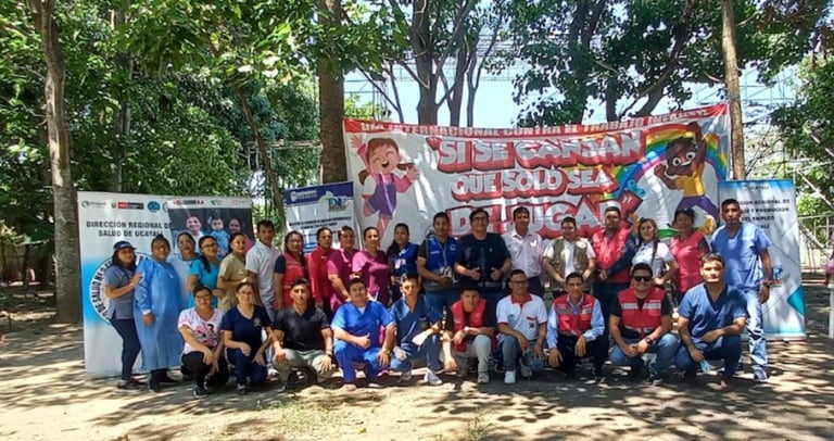 Regional health workers pose before a banner for International Day Against Child Labour in Ucayali.