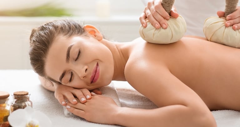 Ontspannende rugmassage met kruidenstempels in een wellness setting.