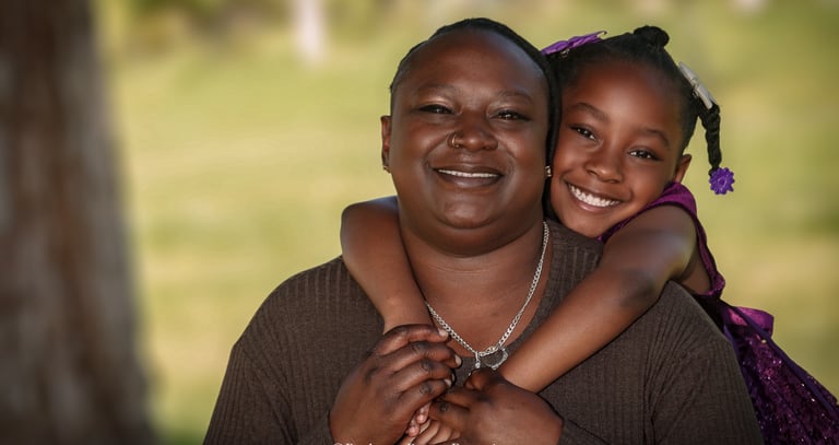 a woman holding a child in her arms posing for a family Portrait