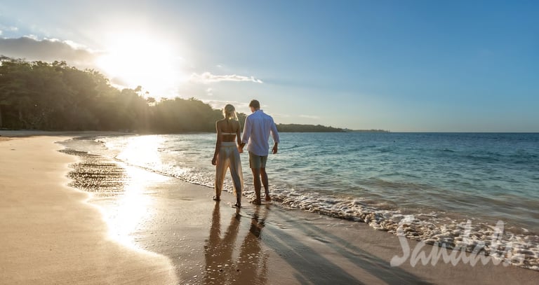 Coastal Vibe Travel - Sandals Honeymoons - a couple holding hands and walking on the beach