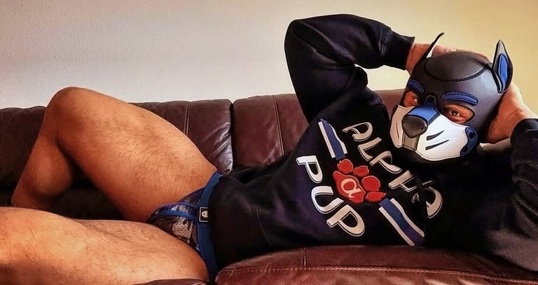 A man reclines, posing in his pup mask.