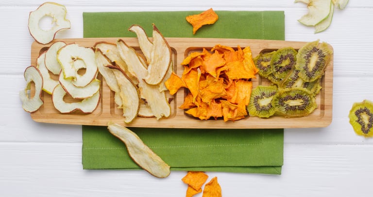 Tabla de picada con manzana, pera, mango y kiwi deshidratados en rodajas.