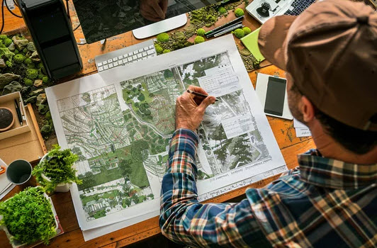 a man is sitting at a desk creating a landscape plan