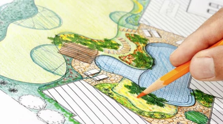 a person drawing a landscaped plan with pencils
