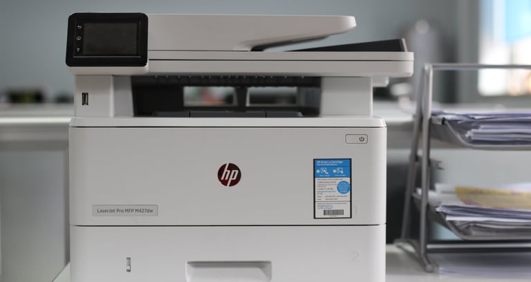 HP LaserJet Pro MFP M427dw wireless monochrome laser printer on a modern office desk.
