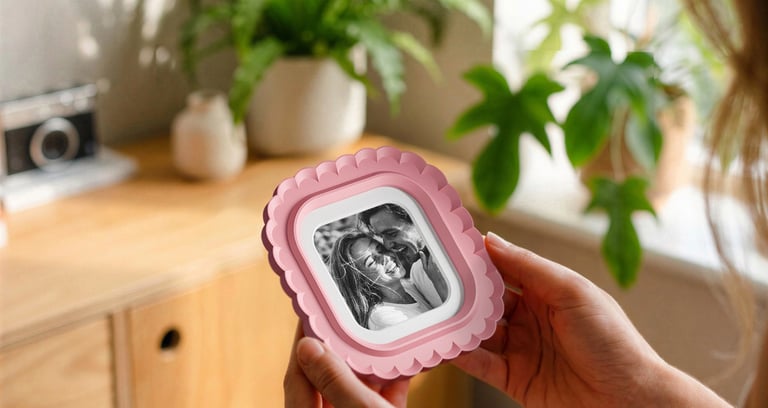 Woman holding a 3D printed photo frame in a cozy home interior with plants