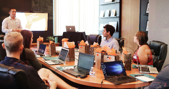 Person preesnting to others at a conference table.