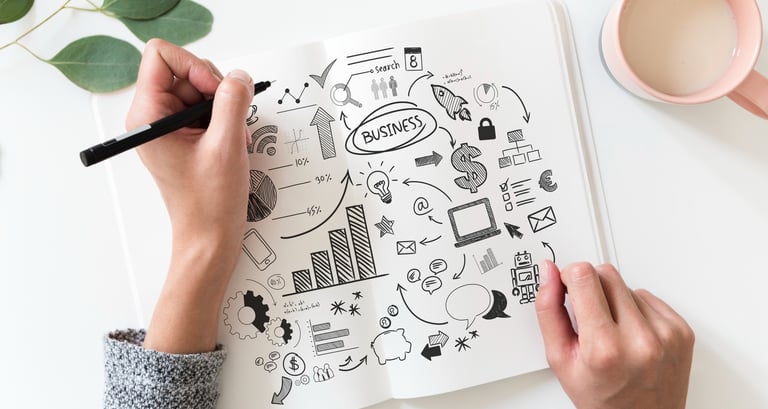 a person's hands holding a pen and drawing on a notebook