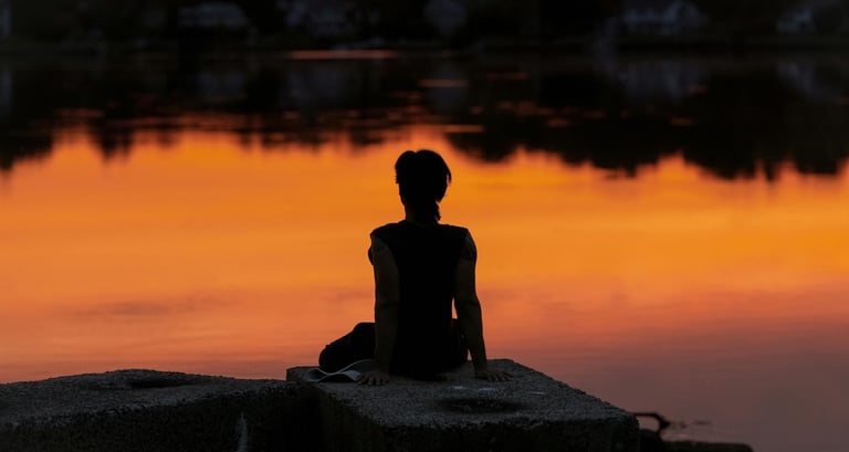 Person sitting peacefully at sunset during a spiritual guidance consultation focused on support