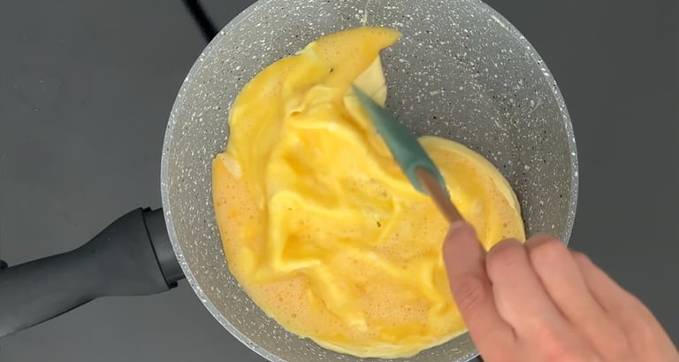 Cuoci l'omelette, usa una spatola per spingere delicatamente i bordi verso il centro creando la form