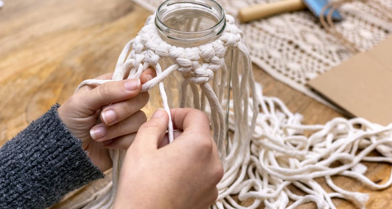 Manos atando un nudo cuadrado con cordón de algodón
