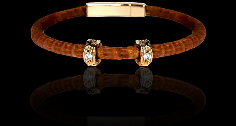 Luxury brown leather cord bracelet with gold accents and crystal studs on black background.