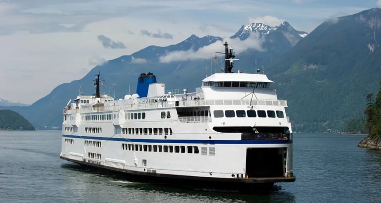 A large white BC Ferries passenger ship sailing through scenic mountain fjords.