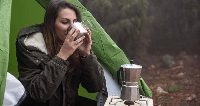 uma mulher sentada em uma tenda com uma xícara de café