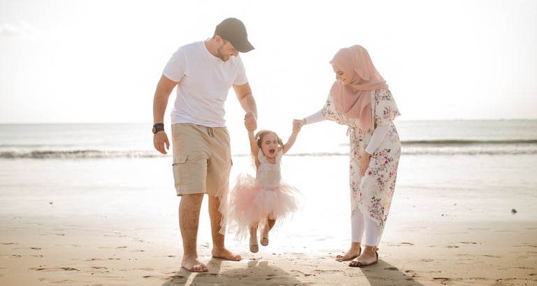 family photography Jimbaran Beach Bali parents holding hands with child on beach